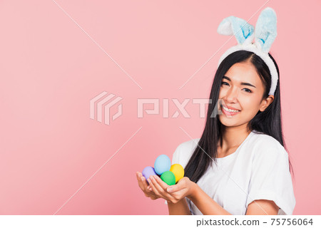 woman smiling wearing rabbit ears holding colorful Easter eggs gift on hands woman smiling wearing rabbit ears holding colorful Easter eggs gift on hands 75756064
