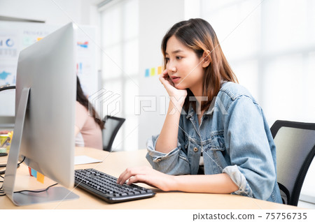 Young asian beautiful woman working on computer at workplace with a business team group Young asian beautiful woman working on computer at workplace with a business team group 75756735