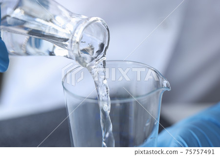 Clear liquid is poured from glass bottle 75757491