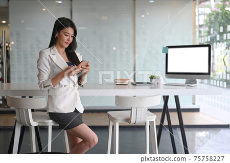 Young woman entrepreneur sitting in modern workplace and using mobile phone. Young woman entrepreneur sitting in modern workplace and using mobile phone. 75758227