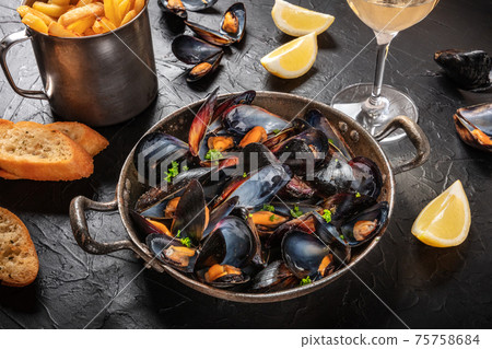 Mussels with wine, lemon, toasted bread and French fries Mussels with wine, lemon, toasted bread and French fries 75758684