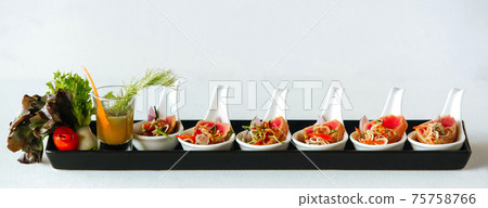 Snacks in white spoons with sauce on long plate Snacks in white spoons with sauce on long plate 75758766