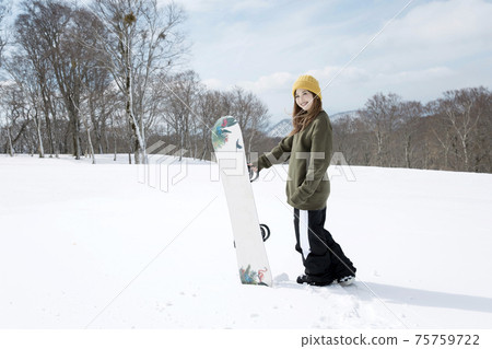 A young woman standing with a snowboard, a snowboard image 75759722