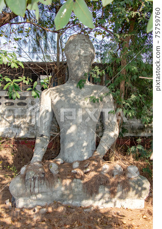 The reconstruction Buddha statue sitting under tropical tree.  75759760