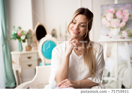 A woman artist with a picture on an easel at home. The painter paints oil paintings. 75759931