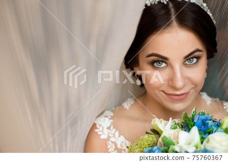 Beautiful woman holding a bouquet of flowers wearing in luxurious wedding dress. Concept of wedding Beautiful woman holding a bouquet of flowers wearing in luxurious wedding dress. Concept of wedding 75760367