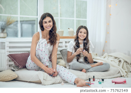 Mom and daughter painting fingernails and toenails 75762549