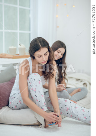 Woman painting toenails girl sitting behind Woman painting toenails girl sitting behind 75762553