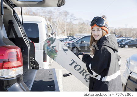 一名年輕女子從汽車後備箱裡拿出滑雪板冬季運動 75762803