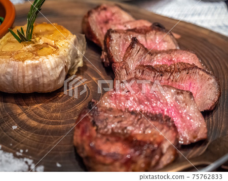 Angus beef steak served with garlic, gravy sauce and spinach in Mediterranean style restaurant Angus beef steak served with garlic, gravy sauce and spinach in Mediterranean style restaurant 75762833