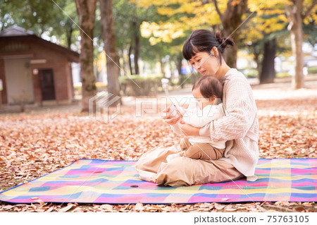 Parents and children playing with smartphones in the autumn park Parents and children playing with smartphones in the autumn park 75763105