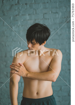 一個男人觸摸手臂的肌肉 75763969