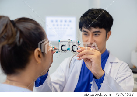 Close up messbrille eye test glasses in a hand of optometrist with blur women background. 75764538