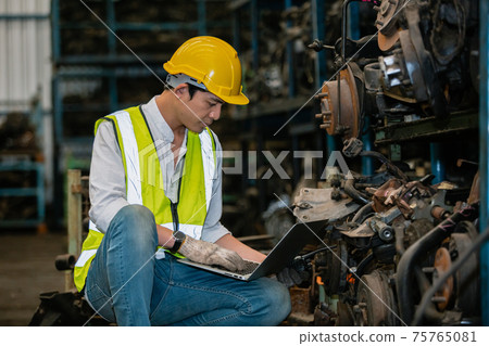engineering man worker wear uniform and helmet using laptop checking automotive parts in warehouse. engineering man worker wear uniform and helmet using laptop checking automotive parts in warehouse. 75765081