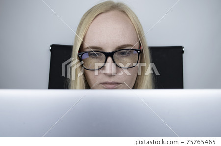 The programmer girl's glasses reflect moving lines of code. Programming, development of applications, sites and more. Software development concept The programmer girl's glasses reflect moving lines of code. Programming, development of applications, sites and more. Software development concept 75765465