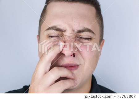The man's nose started bleeding. High blood pressure caused blood vessels to rupture. A thin red trickle flows out of the sinuses. Consequences of vascular problems and severe stress 75765807