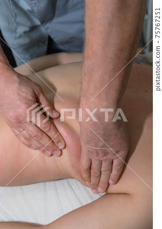 Masseur gives therapeutic massage to man. Male hands do massage of back to patient man. Male patient having massage in clinic. Man relaxing on massage table Masseur gives therapeutic massage to man. Male hands do massage of back to patient man. Male patient having massage in clinic. Man relaxing on massage table 75767251