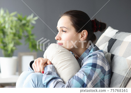 Portrait of young sad woman sitting on couch Portrait of young sad woman sitting on couch 75768161