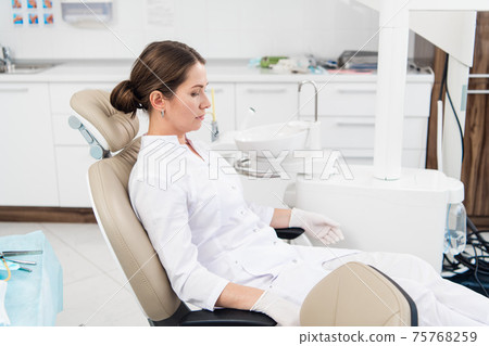 After hours in the dental clinic. A doctor is relaxing in her si After hours in the dental clinic. A doctor is relaxing in her si 75768259