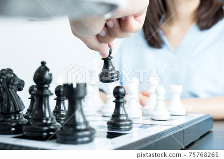 The hands of businessmen moving chess in chess competitions demonstrate leadership, followers, and strategic plans, business success building processes, and teamwork 75768261