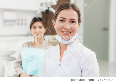 A portrait of a happy female dentist wearing lab coat, while sit 75768298