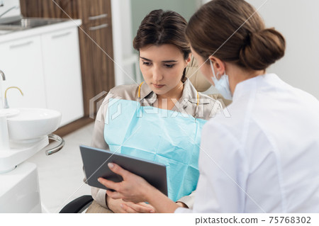 A female patient with a doctor using a tablet in a dental clinic 75768302
