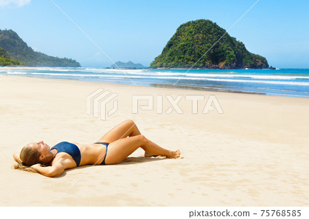 Happy young woman relax on tropical sand beach Happy young woman relax on tropical sand beach 75768585