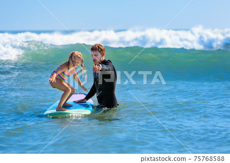 Young surfer learn to ride on surfboard with surf instructor Young surfer learn to ride on surfboard with surf instructor 75768588