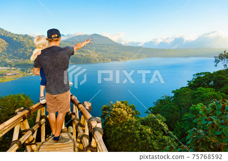 Father with child look at amazing tropical lake in mountains Father with child look at amazing tropical lake in mountains 75768592