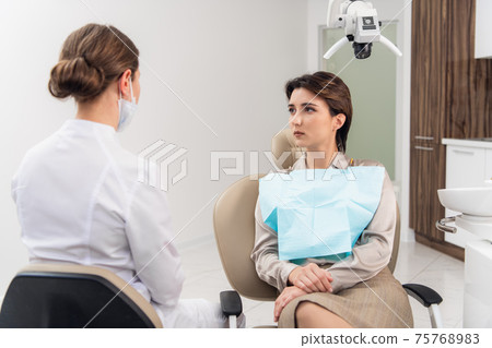 A young female dentist consulting her patient A young female dentist consulting her patient 75768983