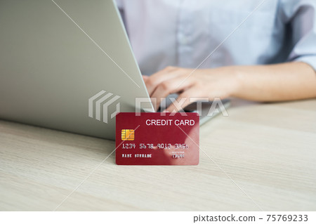 The businesswoman's hand is holding a credit card and using a laptop for online shopping and internet payment in the office The businesswoman's hand is holding a credit card and using a laptop for online shopping and internet payment in the office 75769233