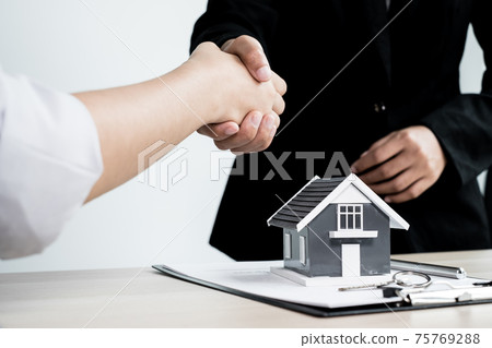 Businessmen and brokers real estate agents shake hands after completing negotiations to buy houses insurance and sign contracts. Home insurance concept Businessmen and brokers real estate agents shake hands after completing negotiations to buy houses insurance and sign contracts. Home insurance concept 75769288
