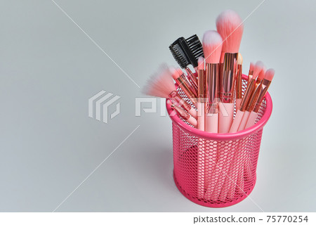 basket with beautiful pink cosmetic brushes on white background 75770254