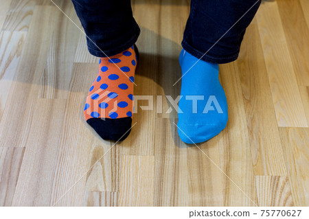 Man wearing different socks standing on the wooden floor. Man wearing different socks standing on the wooden floor. 75770627