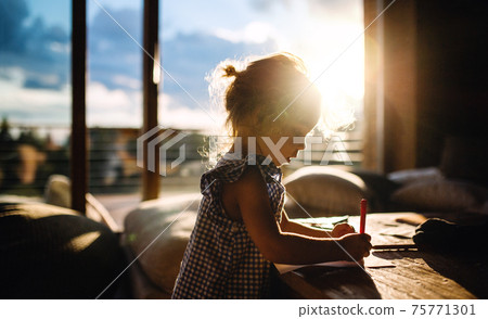 Small girl drawing pictures in wooden cabin, holiday in nature concept. Small girl drawing pictures in wooden cabin, holiday in nature concept. 75771301