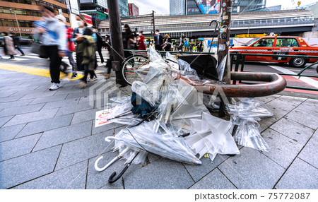 Tokyo cityscape of Japan: The scars of a spring storm ... There is a mountain of umbrellas beside the intersection. On the first day of declaring cancellation, many people ... = March 22 75772087