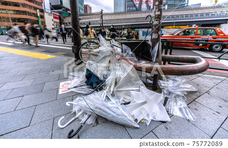 Tokyo cityscape of Japan: The scars of a spring storm ... There is a mountain of umbrellas beside the intersection. On the first day of declaring cancellation, many people ... = March 22 75772089