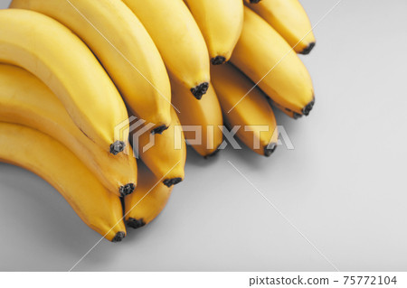 A bunch of fresh yellow bananas on a gray background in the fashionable colors of 2021 75772104