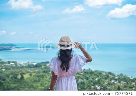 Happy traveler woman enjoy Koh Samui view point, alone Tourist standing and relaxing over ocean in Southern Thailand. Southeast Asia travel, trip and summer vacation concept 75774571