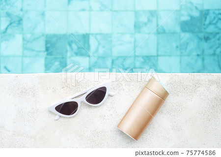 white sunglasses, sunscreen bottle and hat near swimming pool in luxury hotel. Summer travel, vacation, holiday and weekend concept 75774586