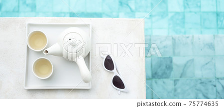 white sunglasses and hot tea pot near swimming pool in luxury hotel. Summer travel, vacation, holiday and weekend concept white sunglasses and hot tea pot near swimming pool in luxury hotel. Summer travel, vacation, holiday and weekend concept 75774635
