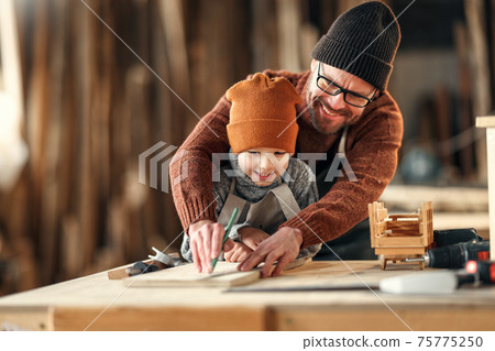 Happy family father and son working together in carpentry workshop 75775250