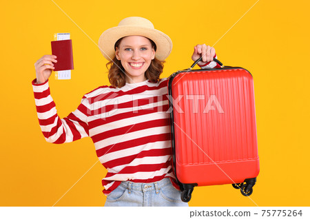 Joyful tourist showing suitcase and passport with tickets Joyful tourist showing suitcase and passport with tickets 75775264