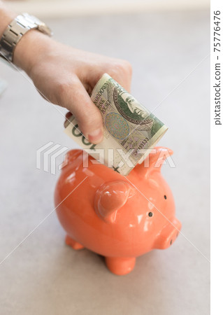 Rich man from Poland. Hand with big silver watch putting a lot of polish money into a piggy bank 75776476