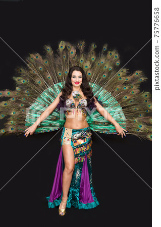 Oriental woman in luxurious peacock feather dress 75776658
