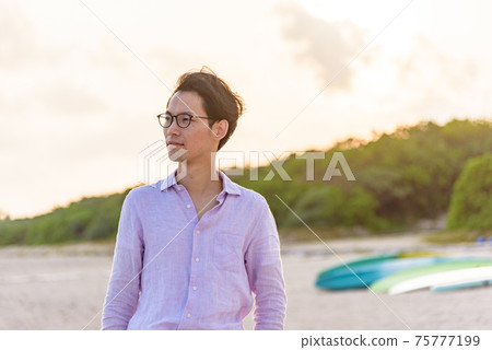A man standing on the beach at dusk A man standing on the beach at dusk 75777199