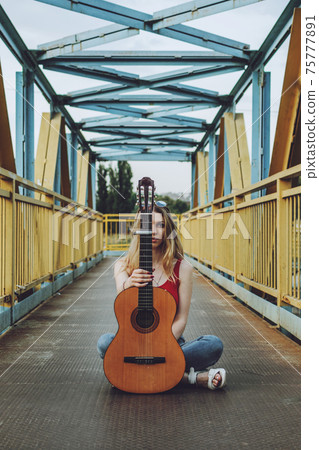 Young Musicians, aspiring musicians, young professional artists, music performing, composer. Young blonde woman with Acoustic guitar outdoor 75777891