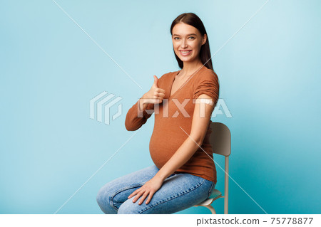 Pregnant Woman Showing Vaccinated Arm Gesturing Thumbs-Up On Blue Background Pregnant Woman Showing Vaccinated Arm Gesturing Thumbs-Up On Blue Background 75778877