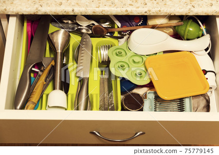 A variety of kitchen utensils in the kitchen drawer. 75779145