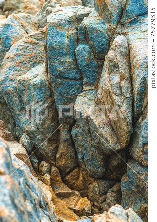 Close up view bright vivid orange brown yellow stone rock shabby cliff cracks texture mountains. Concept of geology, beauty power in nature. Natural summer composition landmark background design 75779315